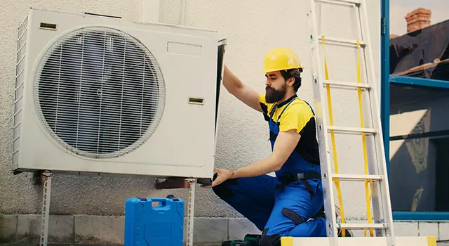 HVAC technician repairing white air conditioner unit outside.